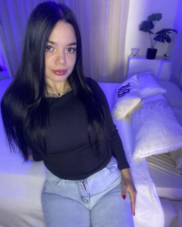 Luna in a black top and jeans in her bedroom